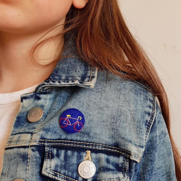 embroidered bike badge on blue felt being worn