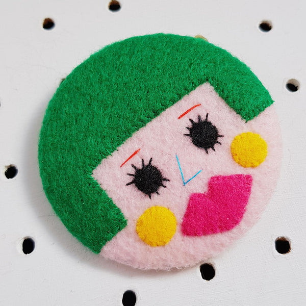 face face badge with green hair and pink lips
