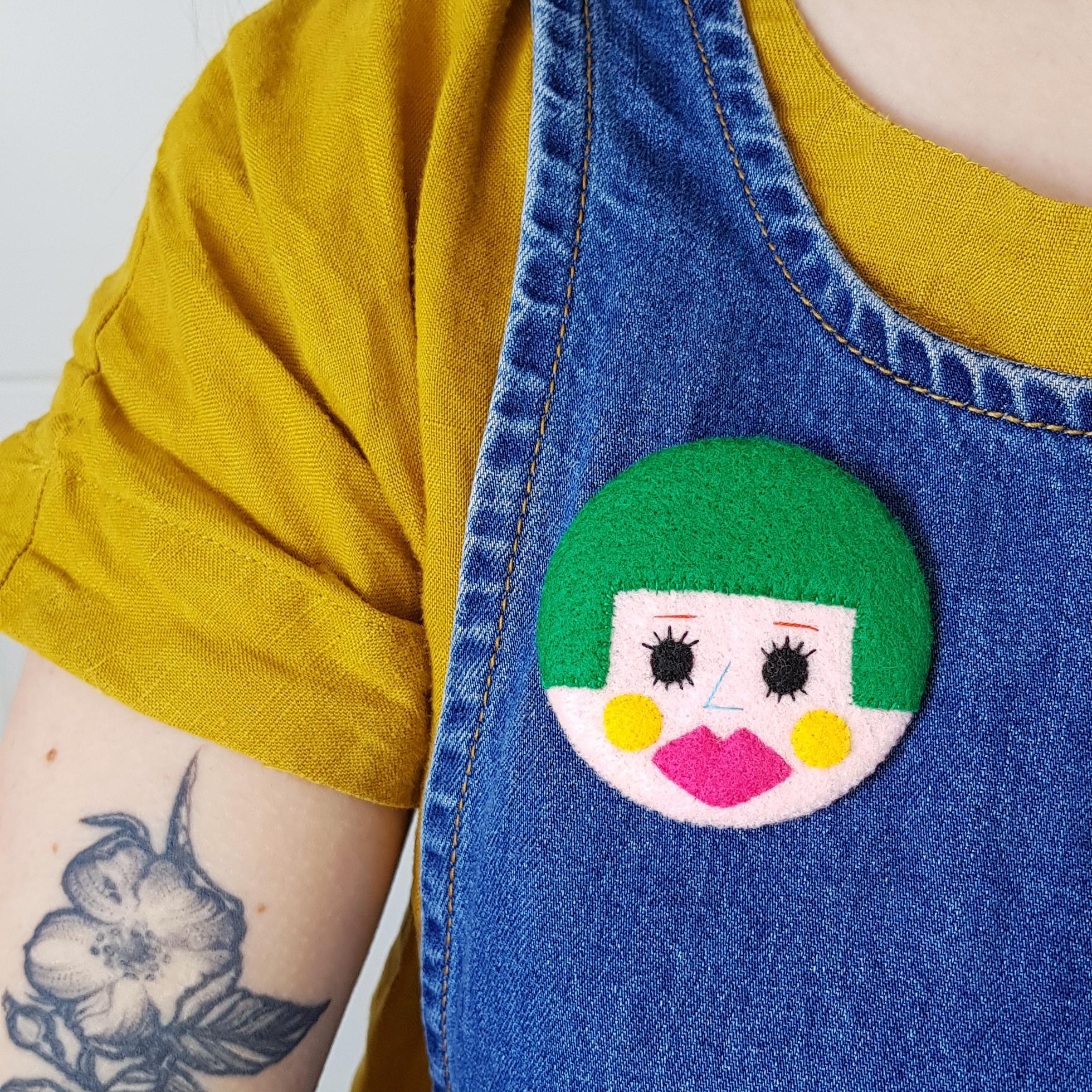 green bobbed hair face badge being worn