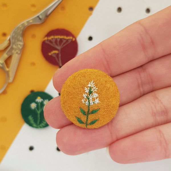 Embroidered mint flower badge on mustard yellow felt