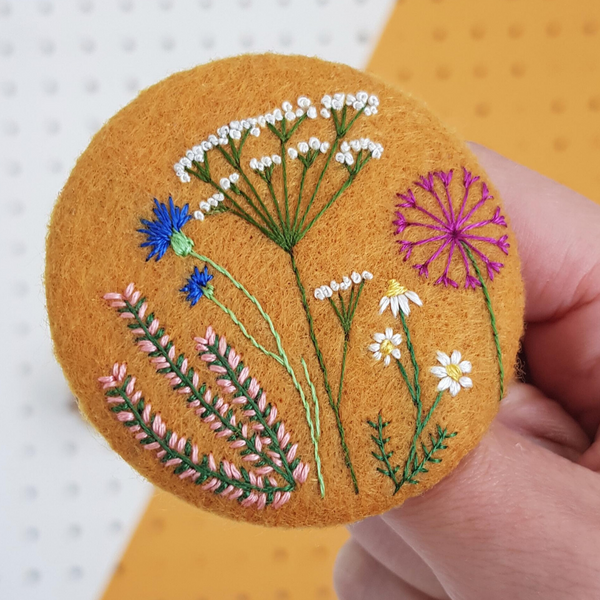large mustard yellow badge with flower embroidery